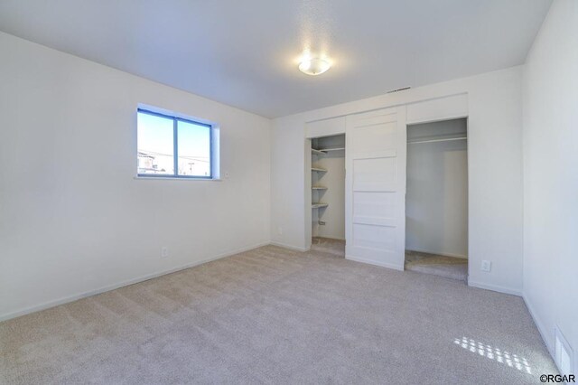 unfurnished bedroom featuring light carpet and a closet