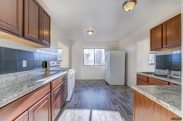 kitchen featuring sink, dark hardwood / wood-style flooring, white appliances, light stone countertops, and decorative backsplash