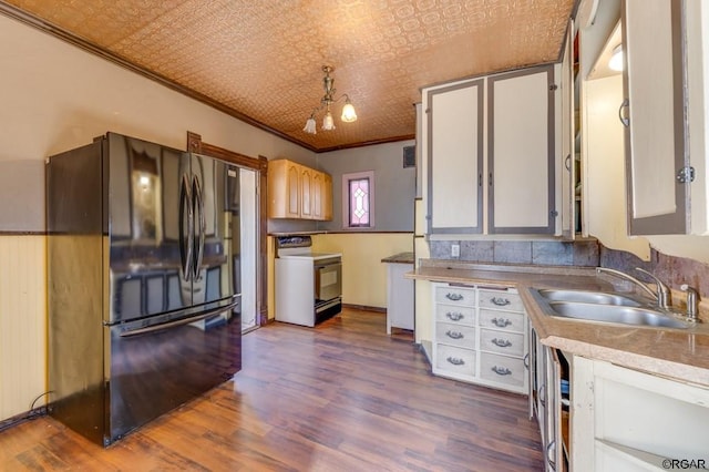 kitchen with sink, crown molding, range with electric stovetop, white cabinets, and black fridge