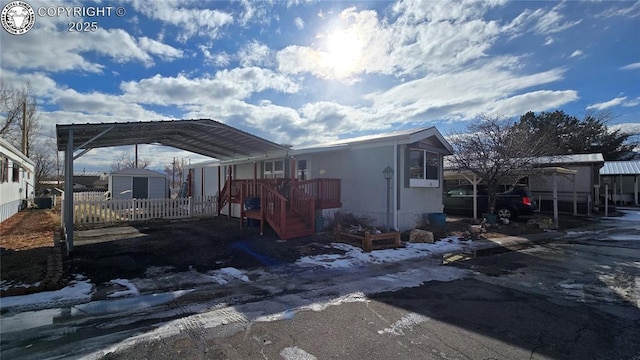 view of snow covered exterior featuring a carport and a storage unit