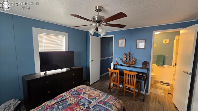 bedroom with dark wood-type flooring, ceiling fan, connected bathroom, and a textured ceiling