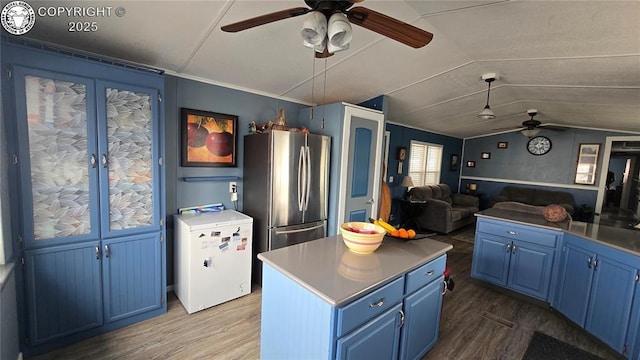 kitchen featuring stainless steel fridge, refrigerator, a kitchen island, blue cabinets, and vaulted ceiling