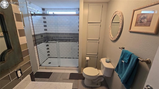 bathroom featuring tile patterned floors, toilet, and a shower with door