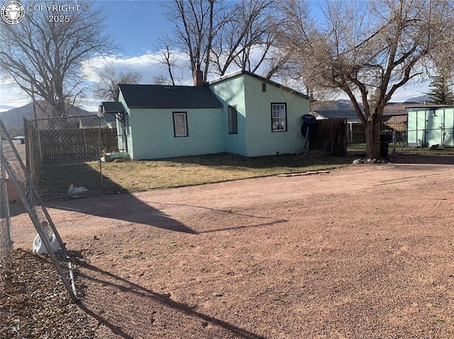 exterior space featuring a chimney, fence, and stucco siding