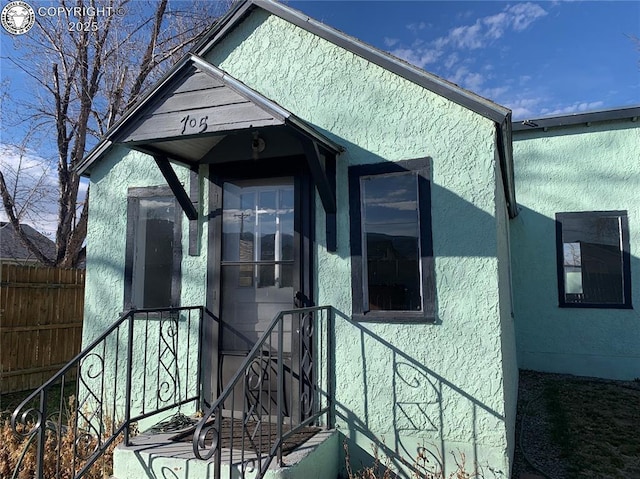 view of side of home featuring fence and stucco siding