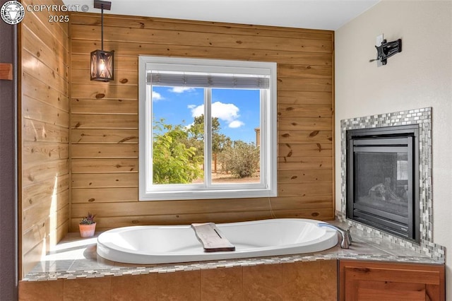 bathroom with tiled bath, a fireplace, and wood walls