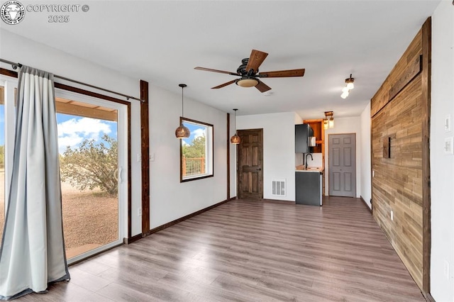 unfurnished living room featuring sink, hardwood / wood-style floors, and ceiling fan