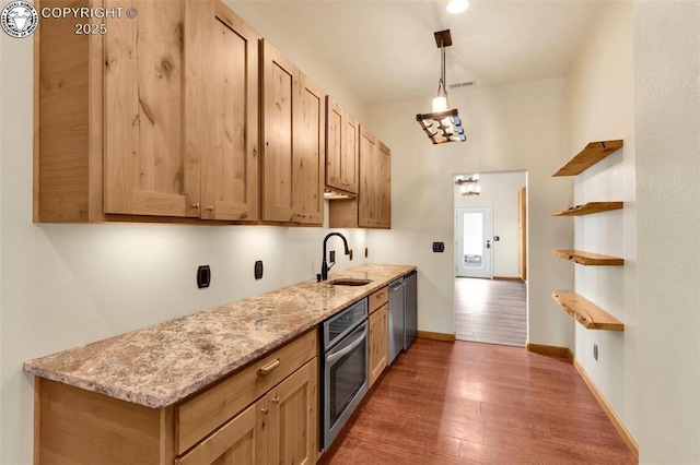 kitchen featuring dark wood-type flooring, sink, light stone counters, hanging light fixtures, and appliances with stainless steel finishes