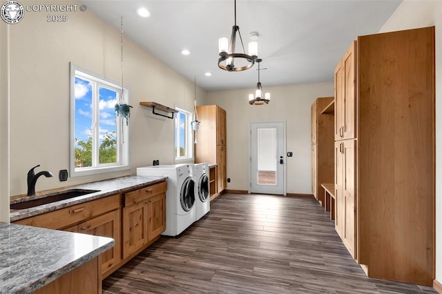 laundry area with sink, dark wood-type flooring, washing machine and dryer, cabinets, and a notable chandelier