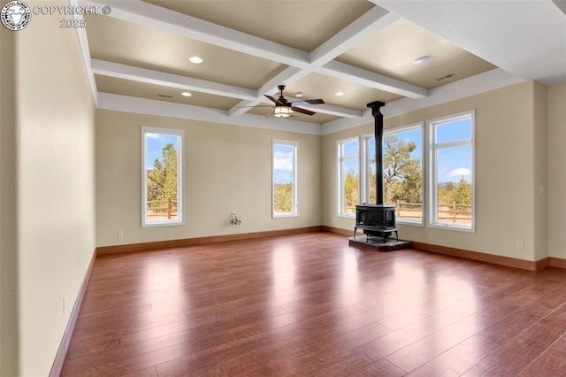 unfurnished living room with beamed ceiling, a wood stove, hardwood / wood-style flooring, coffered ceiling, and ceiling fan