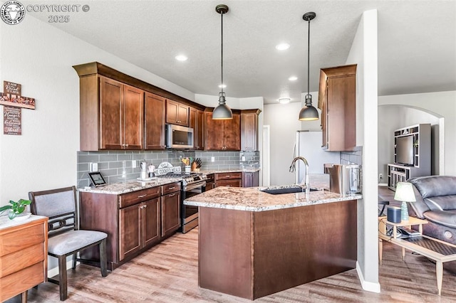 3528 Telegraph Trl, Canon City, CO 81212 - kitchen with appliances with stainless steel finishes, light wood finished floors, light stone countertops, backsplash, and arched walkways
