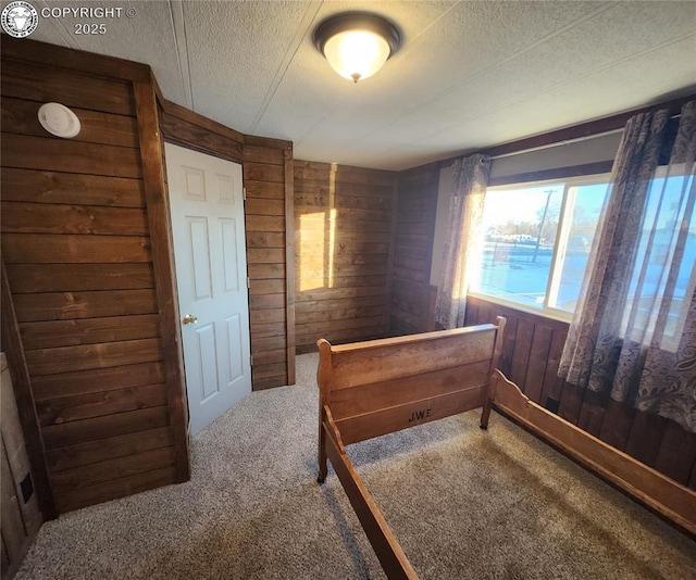 carpeted bedroom with wooden walls and a textured ceiling