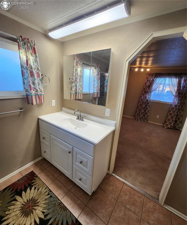 bathroom featuring vanity, a textured ceiling, tile patterned floors, and a healthy amount of sunlight