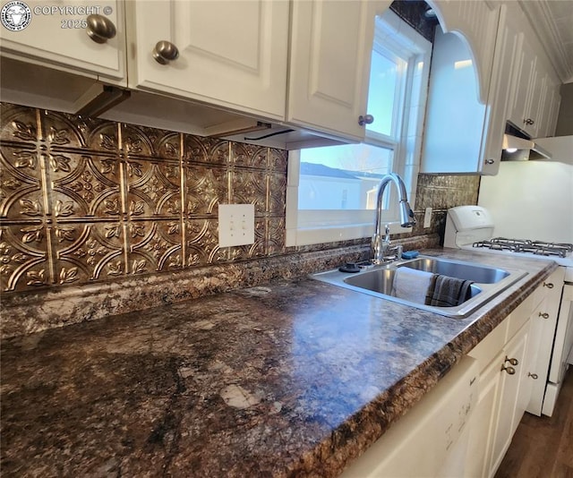 kitchen with sink, backsplash, white cabinets, and range