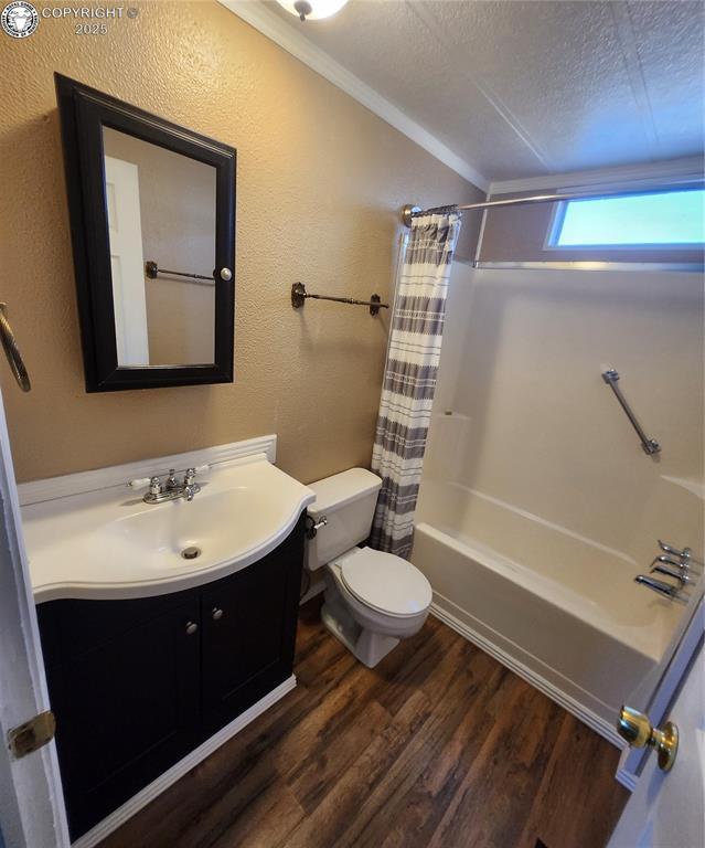 full bathroom featuring hardwood / wood-style flooring, vanity, toilet, shower / bathtub combination with curtain, and a textured ceiling