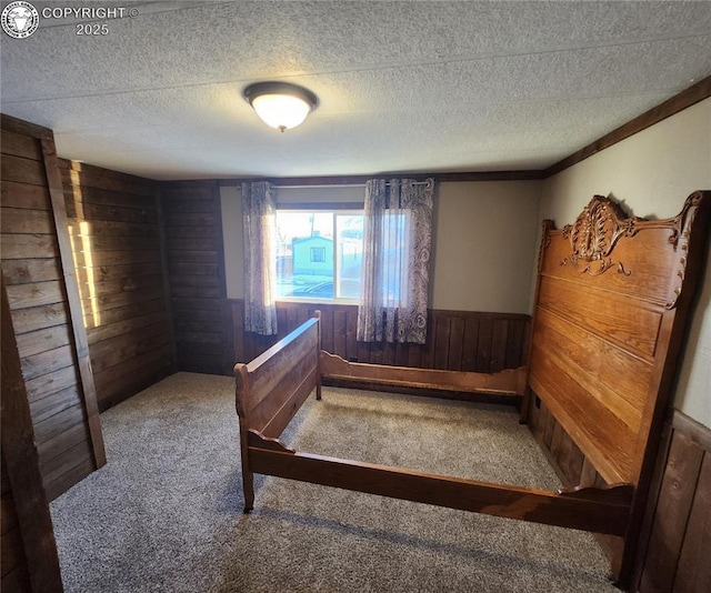 bedroom with carpet, a textured ceiling, and wood walls