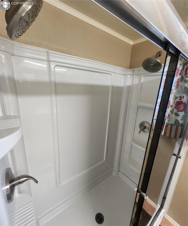 bathroom featuring ornamental molding and walk in shower