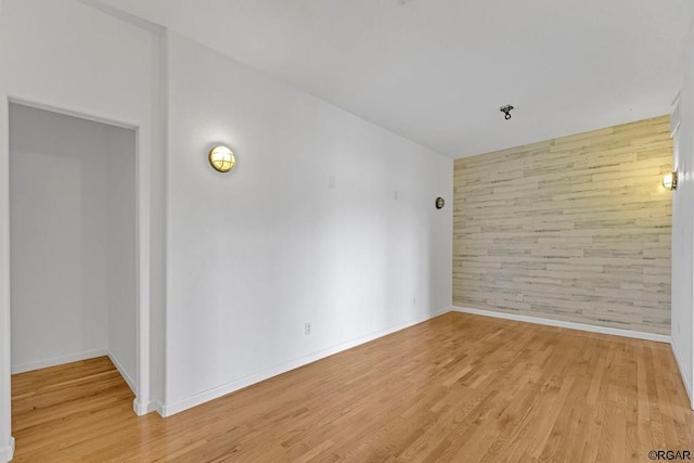 empty room featuring light hardwood / wood-style floors and wood walls