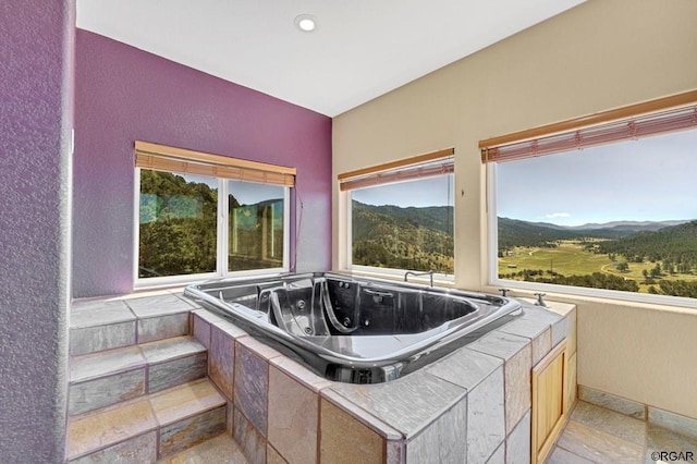 bathroom featuring a relaxing tiled tub and a mountain view