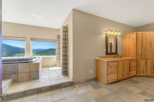 bathroom with lofted ceiling, vanity, a mountain view, and a tub