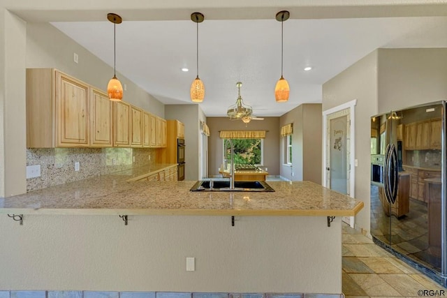 kitchen featuring tasteful backsplash, light brown cabinetry, kitchen peninsula, and black appliances