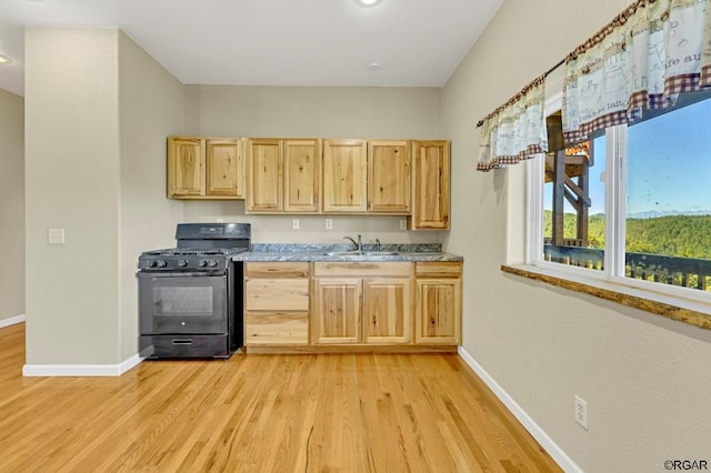 kitchen featuring light brown cabinetry, sink, black range with gas stovetop, and light wood-type flooring