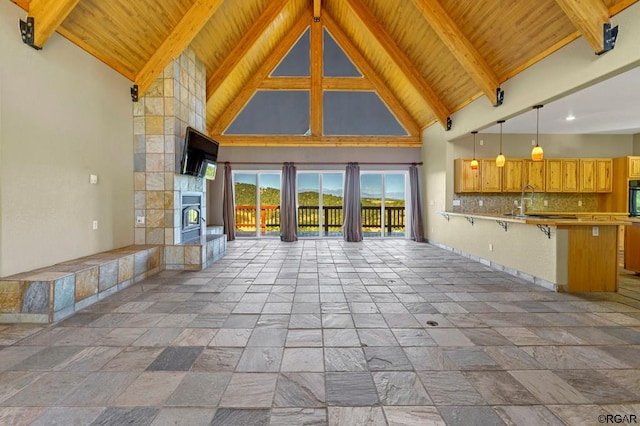 unfurnished living room with beam ceiling, a tiled fireplace, and high vaulted ceiling