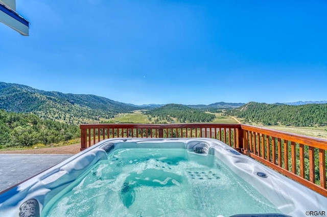 view of pool featuring a hot tub and a deck with mountain view