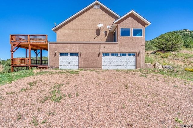 rear view of property featuring a garage and a deck