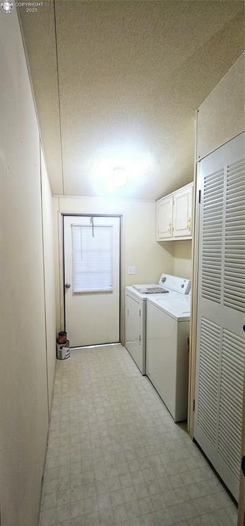 laundry room with cabinets, a textured ceiling, and washer and clothes dryer