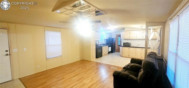 living room with ceiling fan, plenty of natural light, vaulted ceiling, and light wood-type flooring