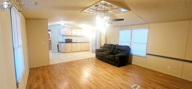 living room featuring vaulted ceiling, ceiling fan, and light hardwood / wood-style flooring