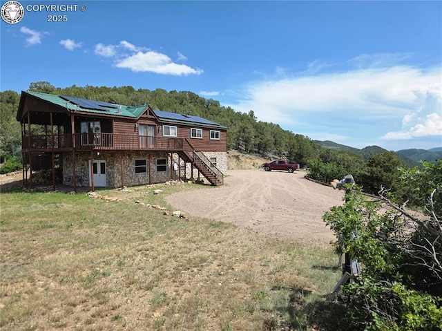 612 Lowry Ln, Canon City, CO 81212 - rear view of property featuring stairway, a deck, a lawn, stone siding, and solar panels