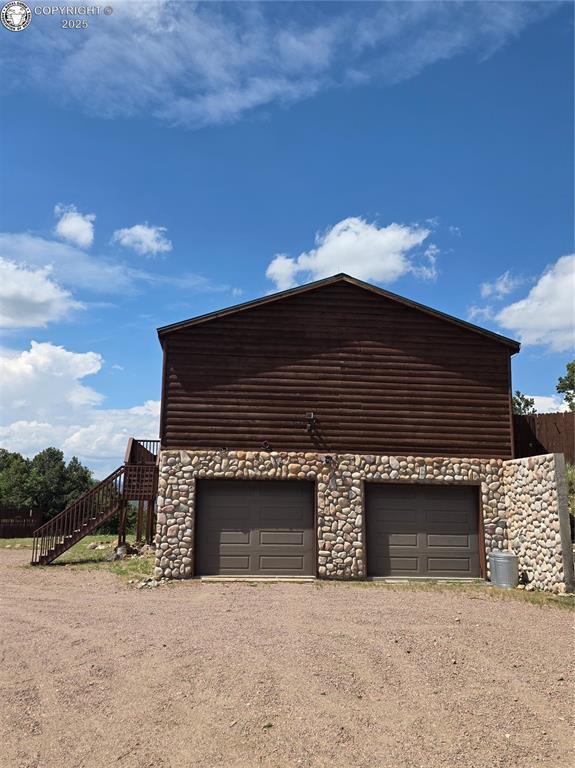 612 Lowry Ln, Canon City, CO 81212 - view of side of property featuring driveway, stairway, a garage, and stone siding