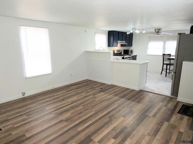 kitchen featuring ceiling fan, appliances with stainless steel finishes, range hood, dark hardwood / wood-style floors, and kitchen peninsula