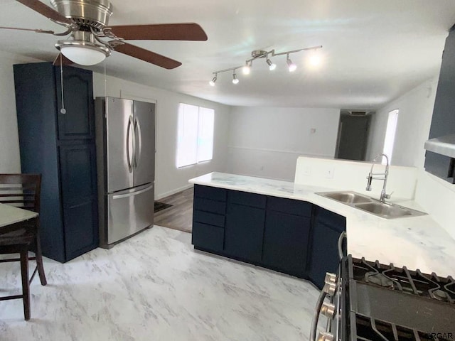 kitchen featuring ceiling fan, sink, and stainless steel refrigerator