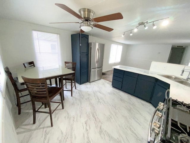 kitchen with gas range, sink, stainless steel fridge, and blue cabinetry