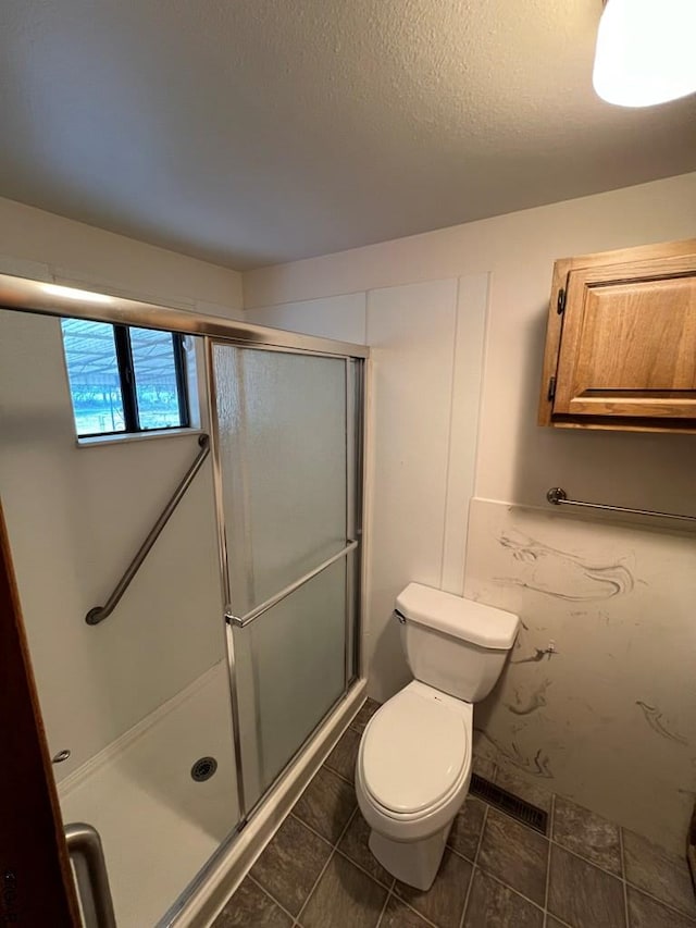 bathroom featuring a shower with shower door and toilet