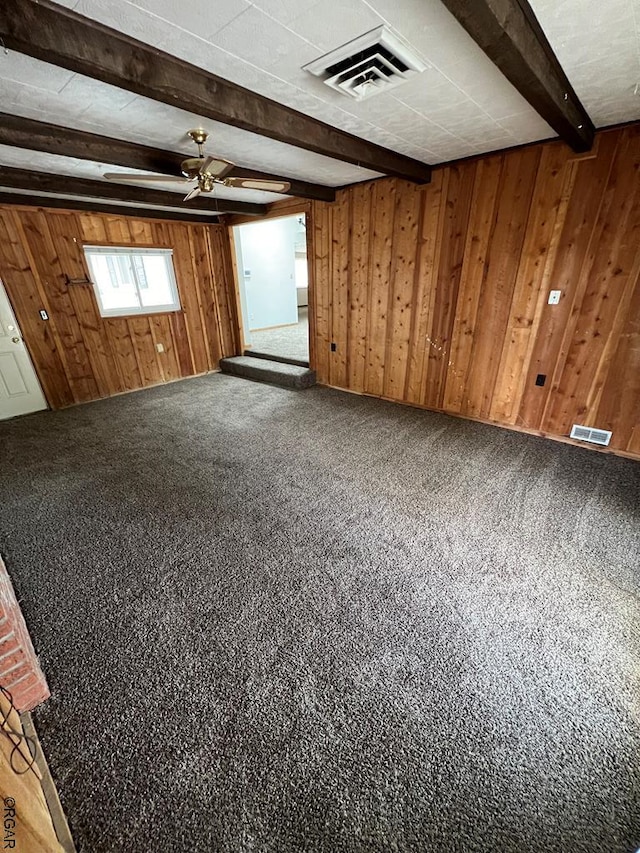 carpeted empty room with beamed ceiling and wood walls