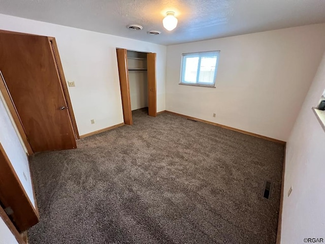 unfurnished bedroom with dark carpet, a closet, and a textured ceiling