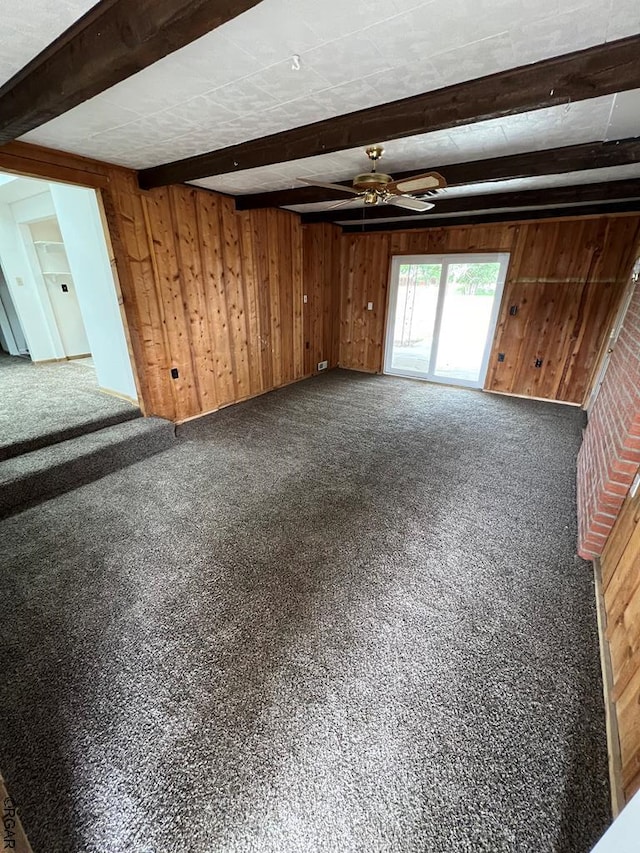 carpeted spare room with ceiling fan, beamed ceiling, and wood walls