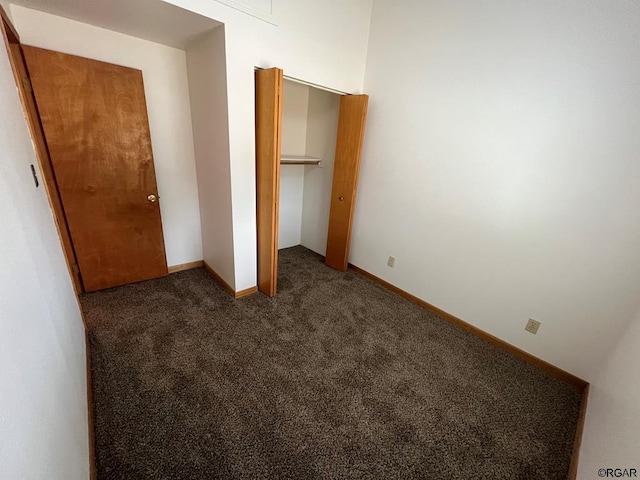 unfurnished bedroom with a closet and dark colored carpet