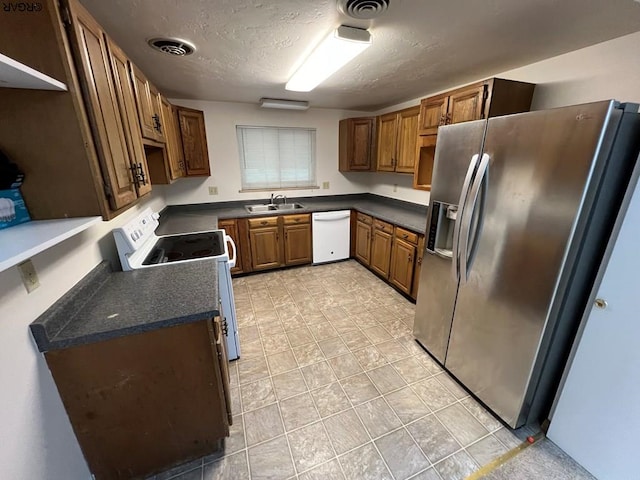 kitchen with white appliances, sink, and a textured ceiling