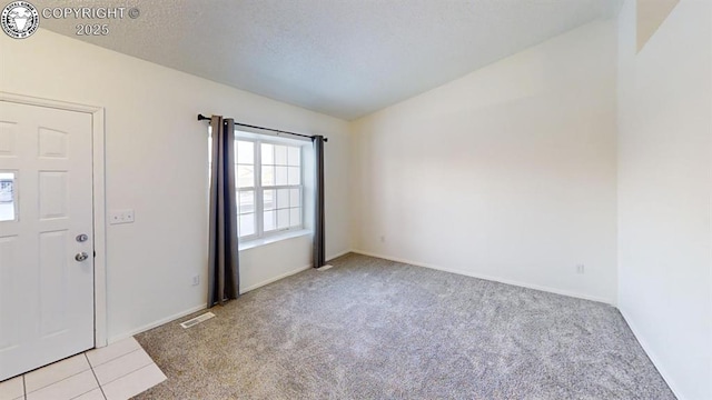 carpeted foyer with baseboards, visible vents, tile patterned floors, vaulted ceiling, and a textured ceiling