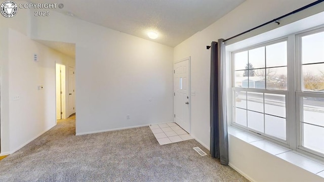 entrance foyer with baseboards, visible vents, light colored carpet, vaulted ceiling, and a textured ceiling