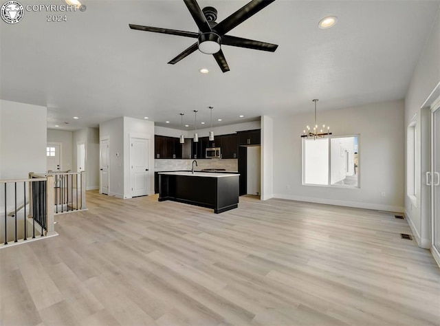 unfurnished living room with sink, ceiling fan with notable chandelier, and light hardwood / wood-style floors