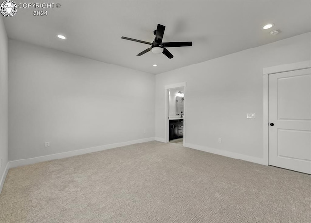 unfurnished bedroom featuring connected bathroom, light colored carpet, and ceiling fan