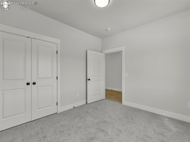 unfurnished bedroom with light colored carpet and a closet