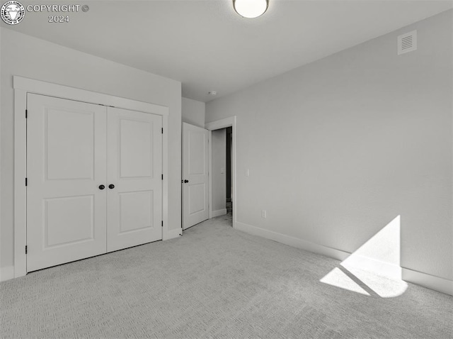 unfurnished bedroom featuring light colored carpet and a closet