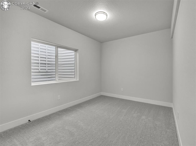 carpeted empty room with a textured ceiling